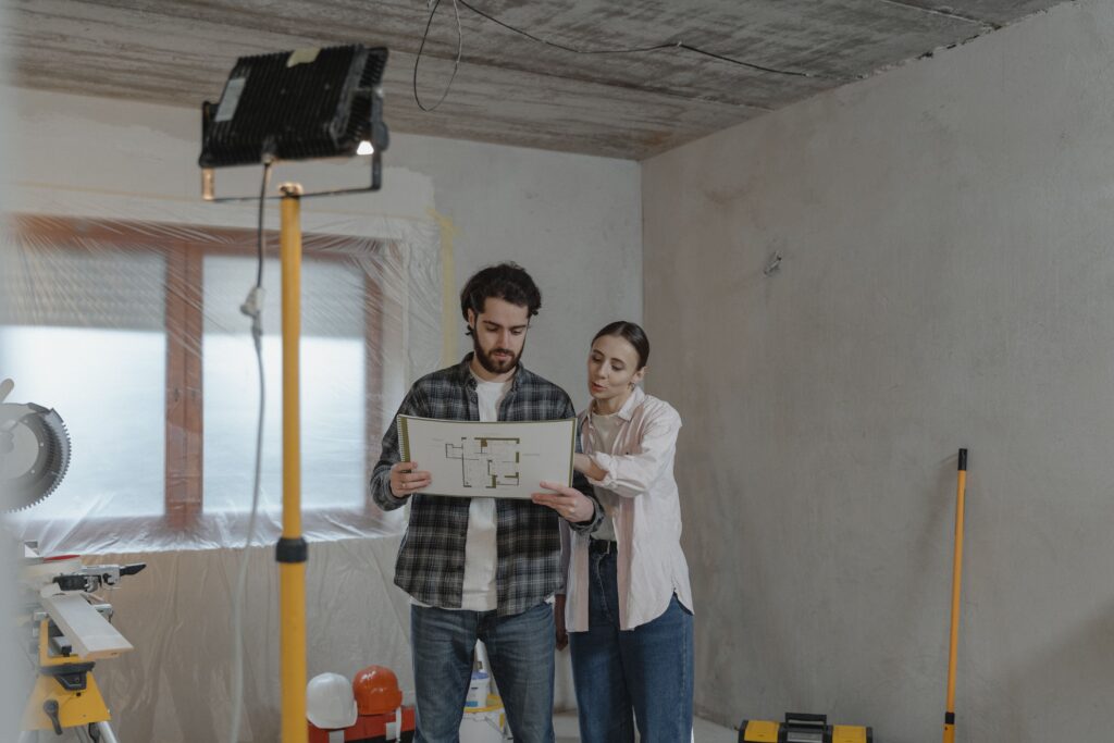 A couple reviewing blueprints in a partially renovated room