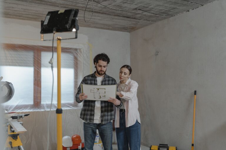 A couple reviewing blueprints in a partially renovated room